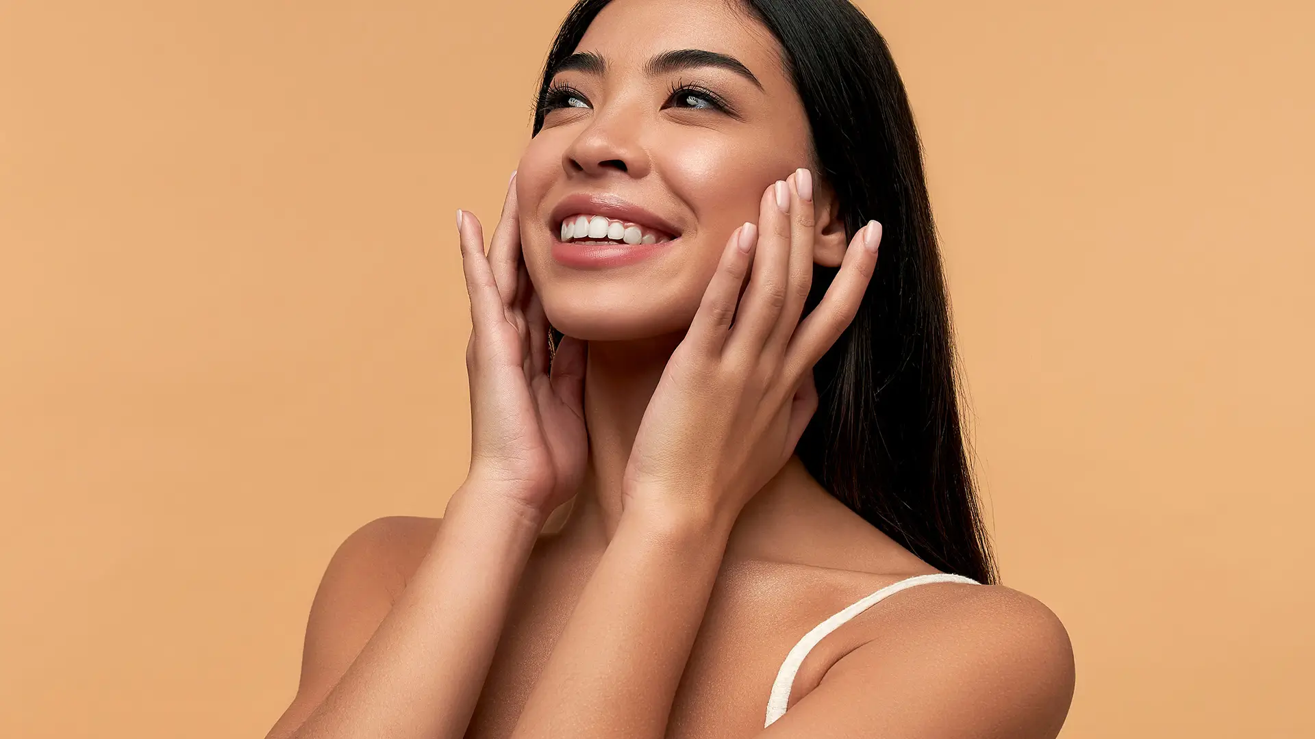 Young Asian woman with glowing skin after facial rejuvenation treatment at Dr. Sanaz Harirchian’s Houston facial plastic surgery clinic.