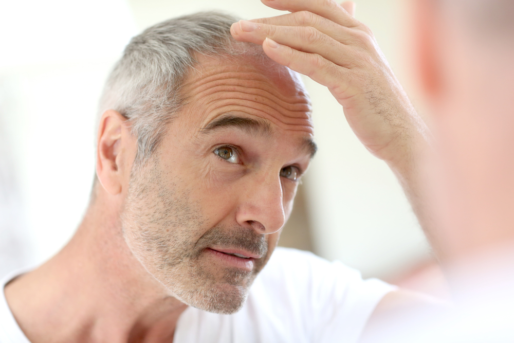 man looking in mirror at hair