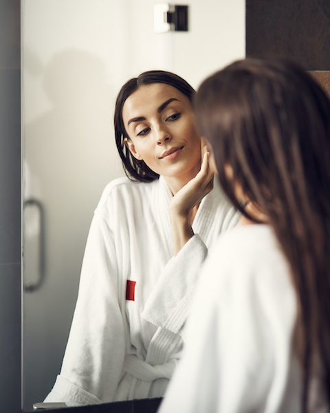 Young woman looking at herself in the mirror