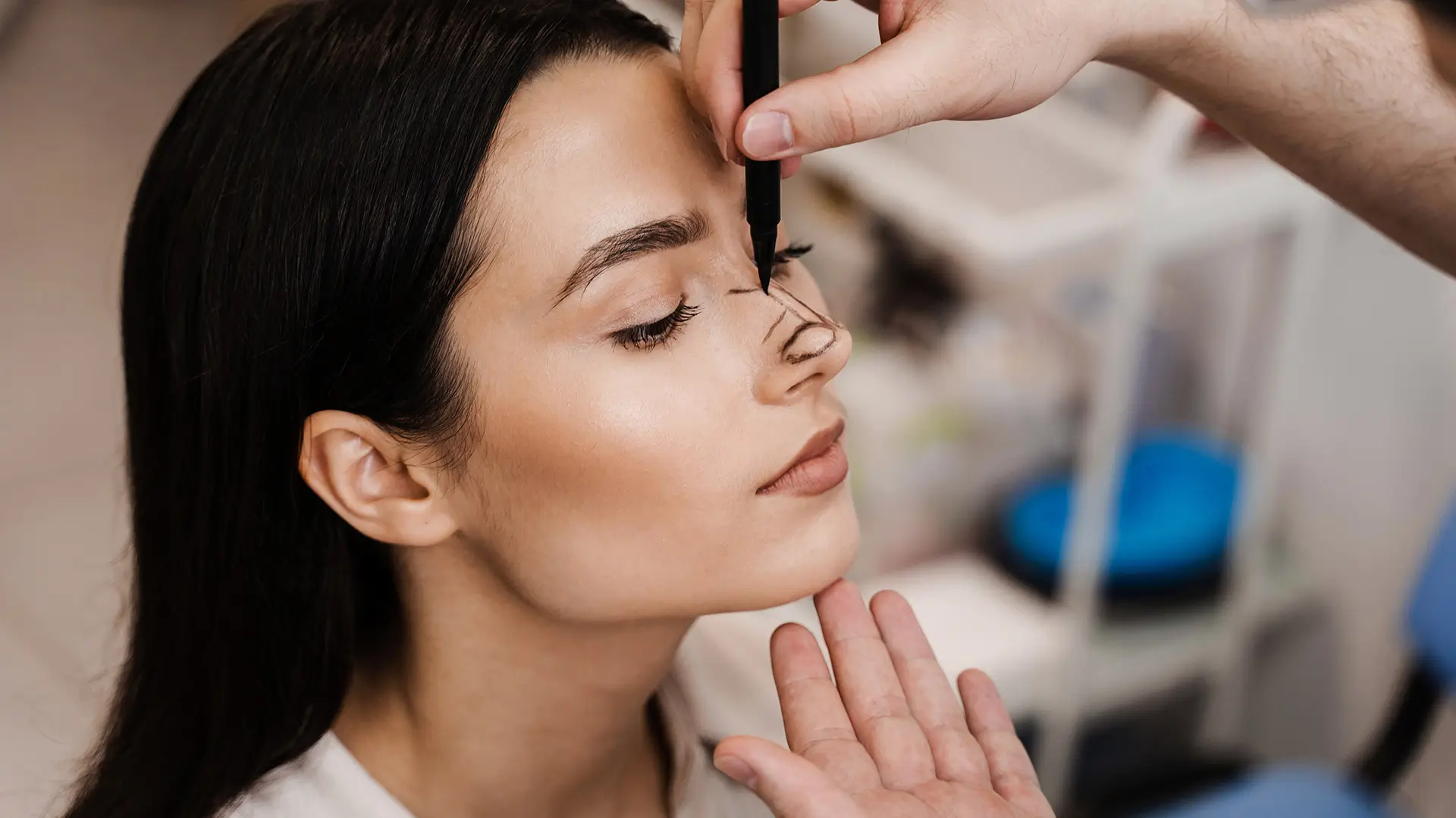 Plastic surgeon drawing surgical guidelines on a woman’s nose before rhinoplasty procedure, highlighting nasal reshaping preparation.